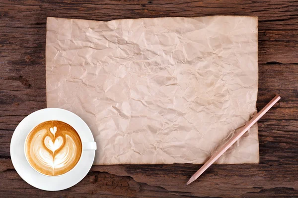 Blank paper with pencil and a cup of coffee on wooden