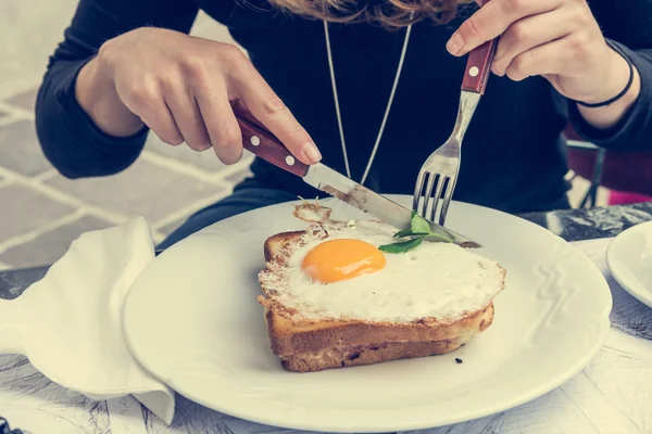 Attractive woman enjoying sunny side up egg on french toast.