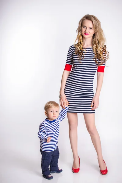 Mother with her son standing over the white background, blond, smiling, striped clothes, the family sailor
