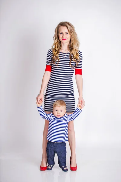 Mother with her son standing over the white background, blond, smiling, striped clothes, the family sailor