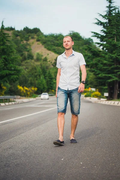 Beautiful young girl goes to a meeting, denim shorts, man smiling, mountains in the background, yellow bush, yellow flowers, spring, autumn