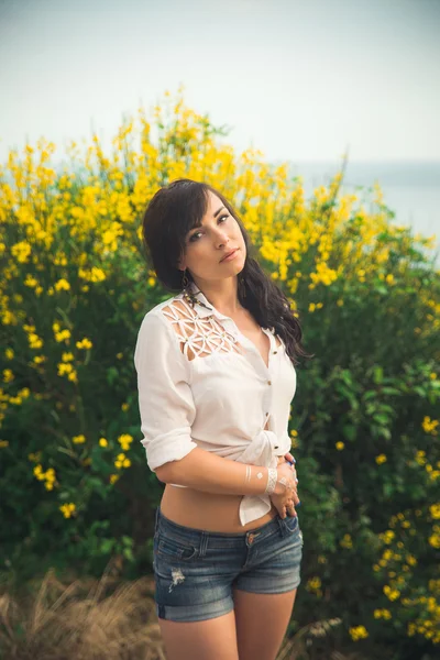 Beautiful young girl goes to a meeting, denim shorts, man smiling, mountains in the background, yellow bush, yellow flowers, spring, autumn