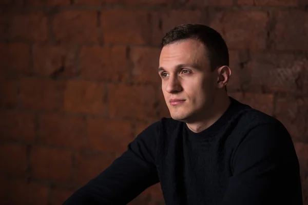 Wealthy man, dark background, short-haired man, businessma, a man in a dark  sweater, blazer, looking directly into the camera, stern look, business, brick wall, dark background, red brick, bright smile,