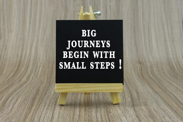 Art board, wooden easel, front view with word Inspiration quote : Big journeys begin with small steps