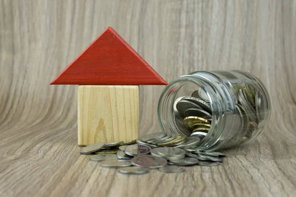 House Wooden Block with coins on a wooden background. Housing Loan concept. Selective focus