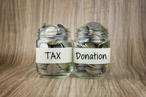 Two glass jars with coins labeled TAX and Donation. Financial Conceptual