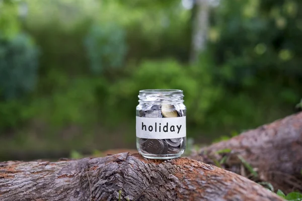 Coins in glass with Holiday label against bokeh background.Financial concept.Selective focus.