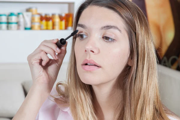 Woman putting on mascara