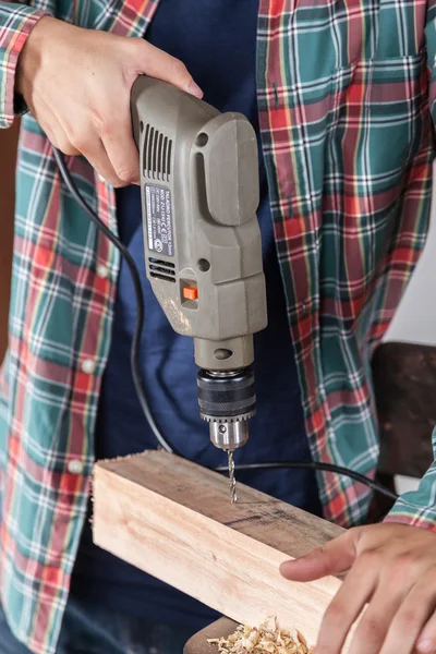 Carpenter drilling wood with drill