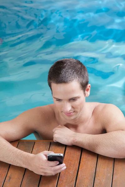 Man play with mobile phone in a pool