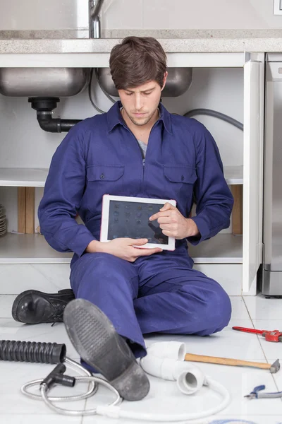 Plumber with a ipad sitting on the floor