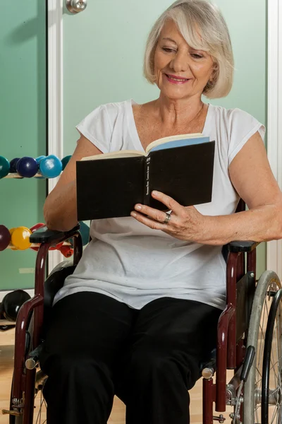 Elder woman in a wheelchair reading a book