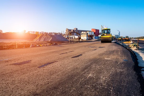 Sunset above the road rollers working on the construction site