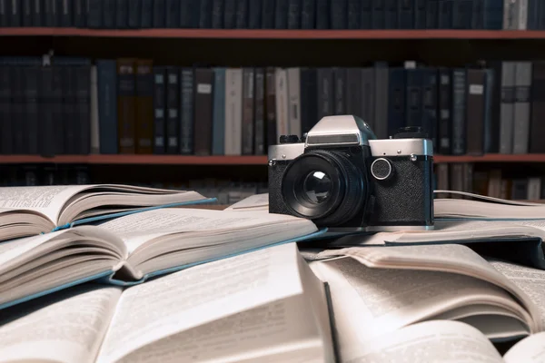 Old photo camera  is on many  open books piled up with many book
