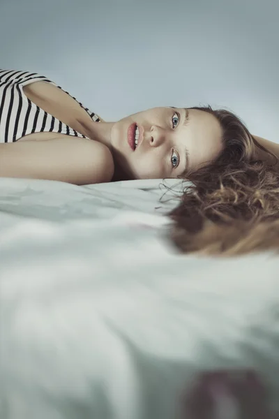 Cute Young woman in bed with long ringlets hairs