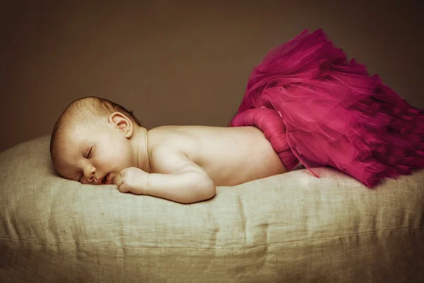 1-2 month old baby  sleeping on pillow in ballerina skirt