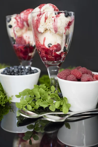 Fruits in white bowls with silver spoons, and ice cream in glass.