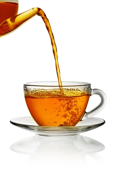 Tea pouring into glass cup isolated in white