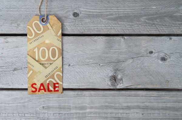 Canadian sale tag on brown vintage paper against wooden backgrou