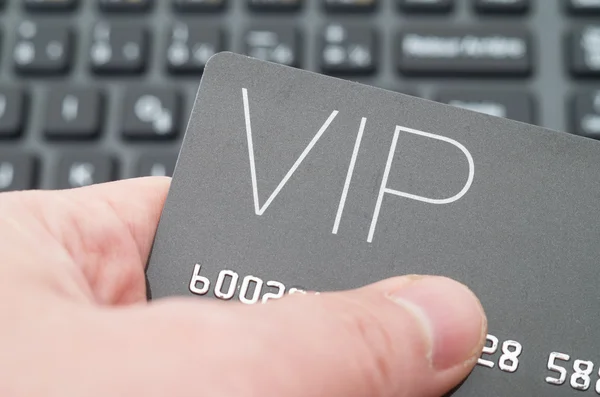 Hand holding VIP card against keyboard background
