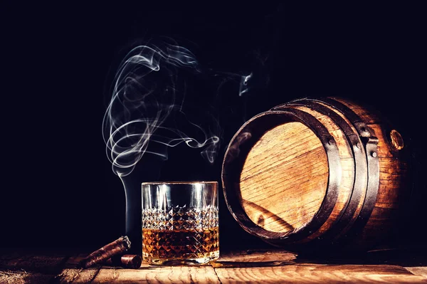 Glass of alcohol and smoking noble cigar on a black background