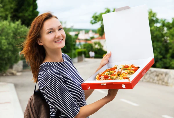Happy young woman holding hot pizza in box