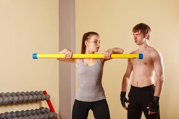 Trainer explains the exercise with girls fitbar.