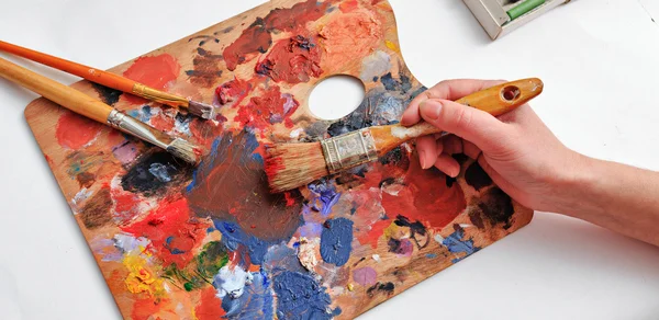 Artist\'s hand with brushes and palette of colors
