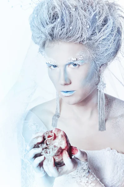 Snow queen with an unusual makeup and heart in hands