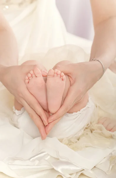 Mother holds feet of her daughter.