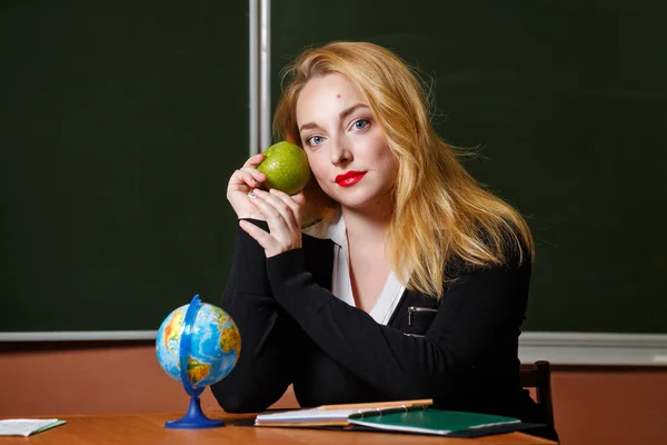 Geography teacher holding a green apple.