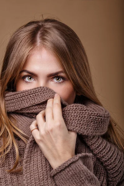 Girl hides her face in a warm sweater. We see only the eyes.