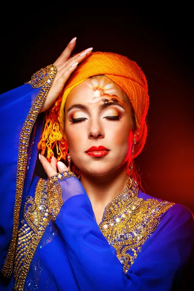 Portrait of oriental beauty in a turban and face art.