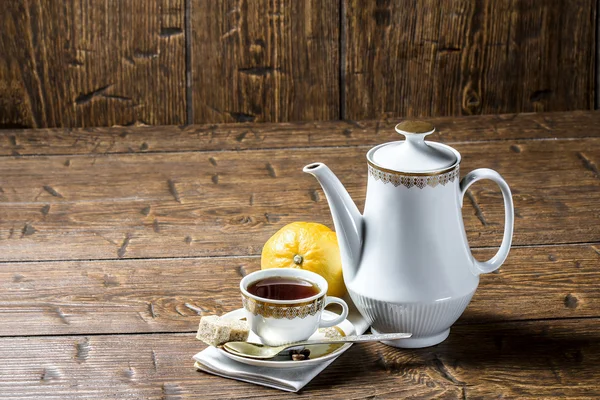 Coffee pot with coffee Cup and lemon on wooden table