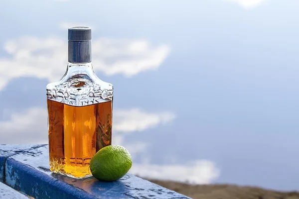 Bottle tequila and lime on shore of lake