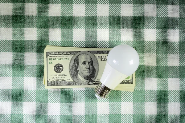 Led light bulb lying on the stack of dollars