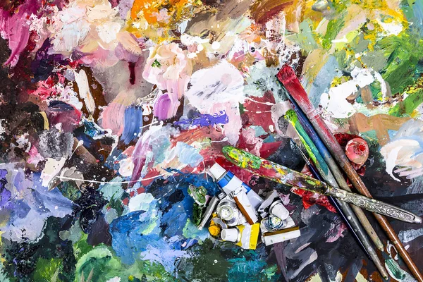 The palette of artist for mixing paints and a brush with a knife