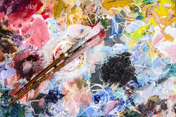 The artist palette with a Cup of mixing oil paints and two brush