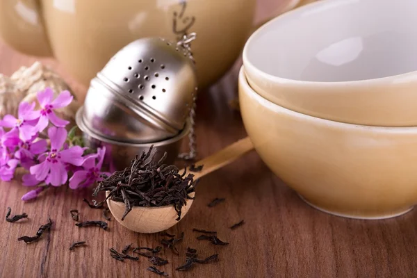 Dry tea in spoon in front of tea set