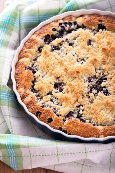 Fresh blueberry pie in blue baking dish on checkered towel