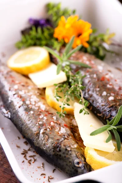 Raw throuts in ceramic pan with lemon butter and herbs