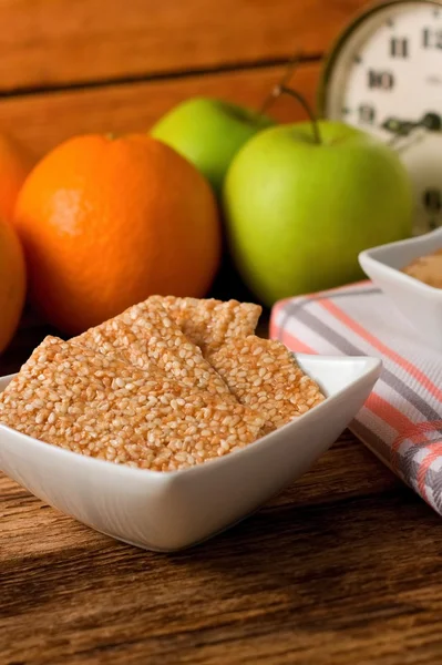 Biscuits from sesame seeds and honey and fruit in background