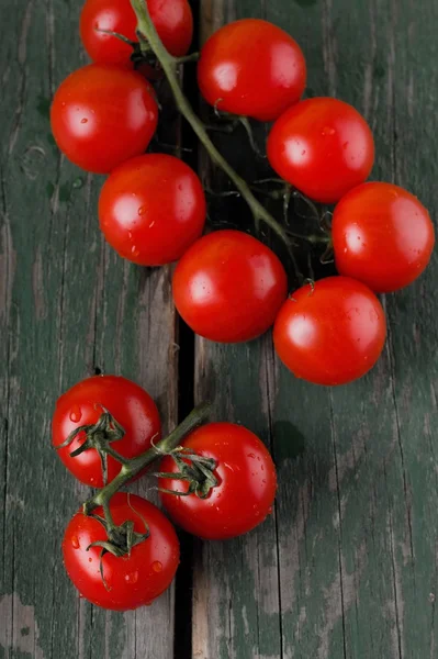 Several red cherry tomatoes on branch placed on green table