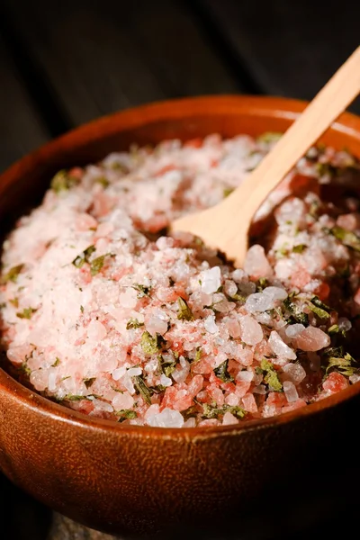 Pink sea salt with herbs in wooden bowl