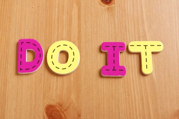 DO IT, spell by woody puzzle letters with woody background