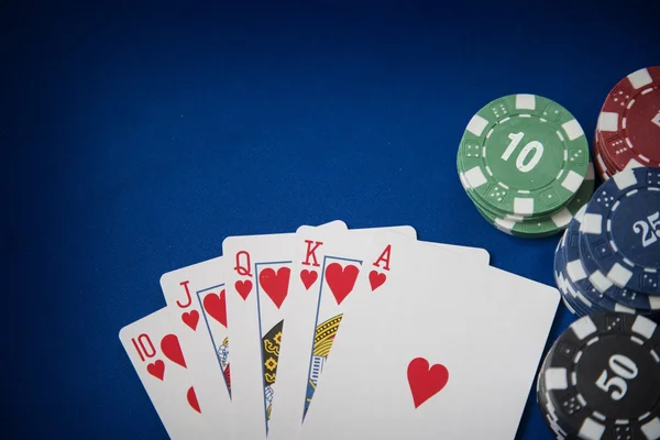 Gambling chips and poker card on blue felt background