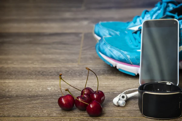 Sport shoes, phone and smart watch with set for sports activities on floor.