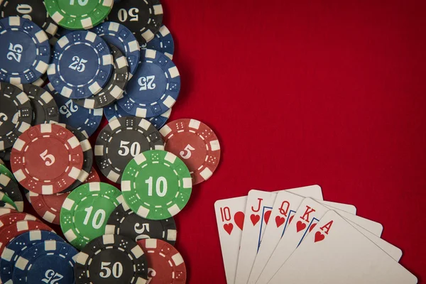 Gambling chips and card for poker on red felt background