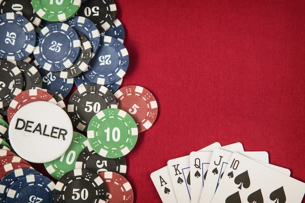 Gambling chips, dealer chip and card for poker on red felt background