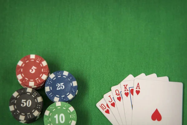 Gambling chips and card for poker on green felt background